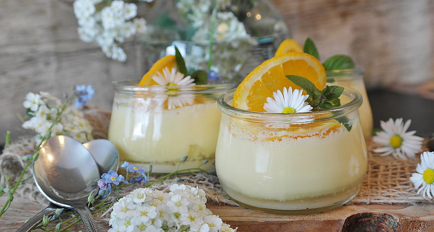 Creamy orange dessert in glass jars with flowers