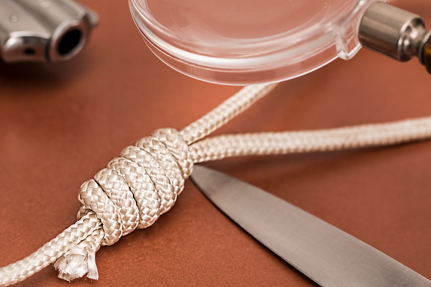 Forensic investigation concept with rope knot, knife, and magnifying glass
