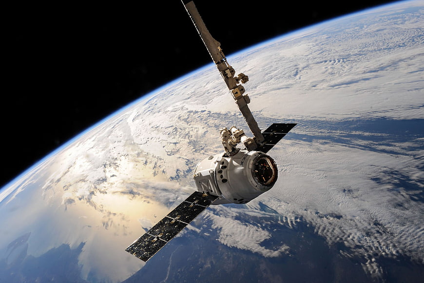 Spacecraft orbiting Earth with solar panels and robotic arm