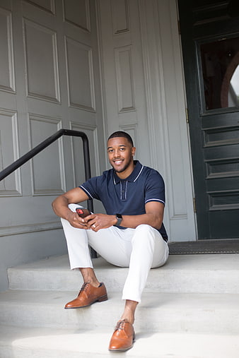 Smiling young man sitting on steps with smartphone