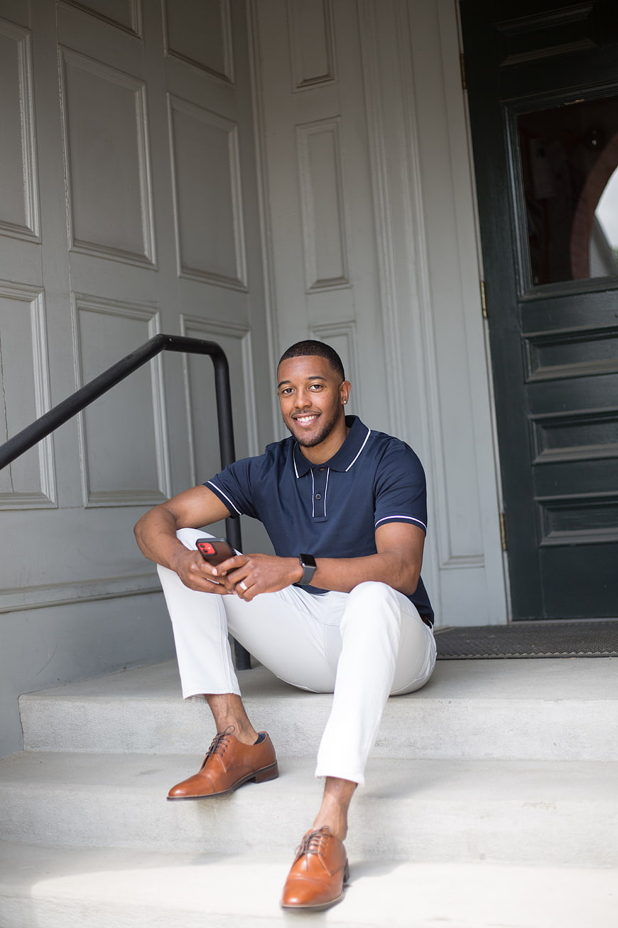 Smiling young man sitting on steps with smartphone