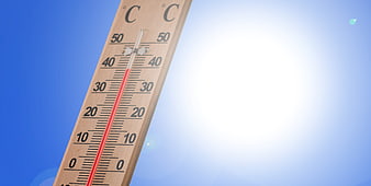 Wooden thermometer showing high temperature against bright blue sky