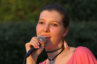 Young woman singing into microphone at outdoor concert