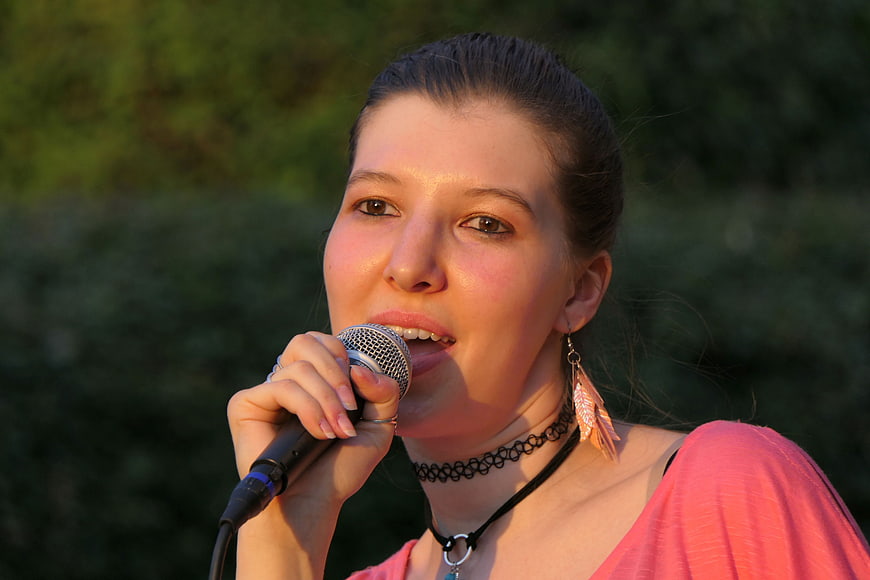 Young woman singing into microphone at outdoor concert
