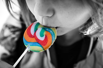 Close-up of girl licking colorful swirl lollipop