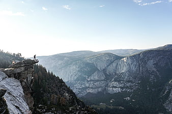 Hikers on Rocky Cliff Overlooking Mountain Valley Landscape