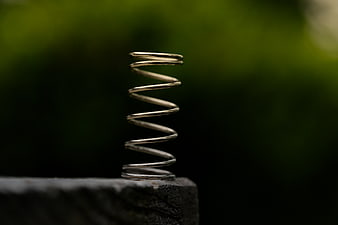 Metal spring on stone with blurred green background