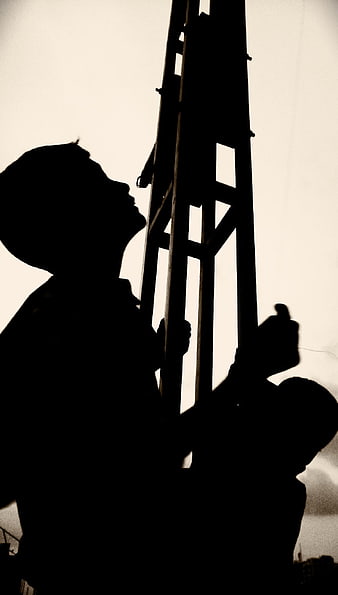 Silhouette of construction workers carrying a ladder