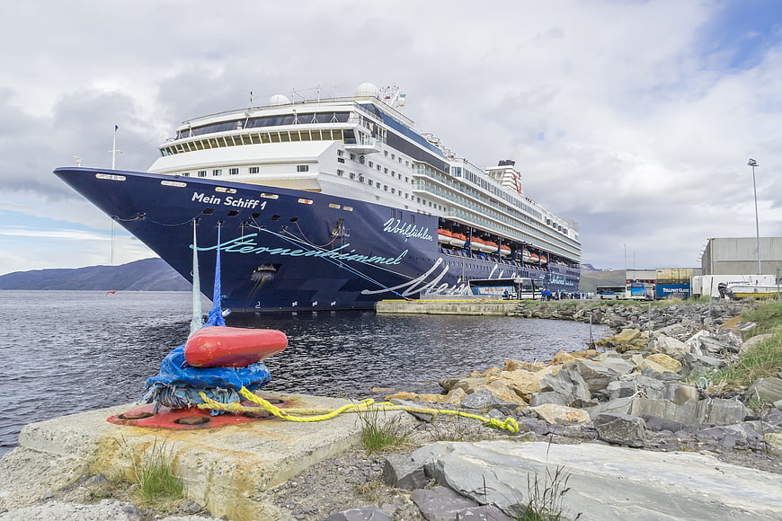 Mein Schiff 1 cruise ship docked at a rocky harbor