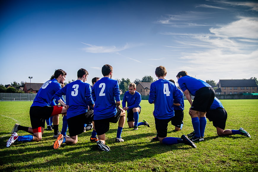 Soccer team huddle on grass field
