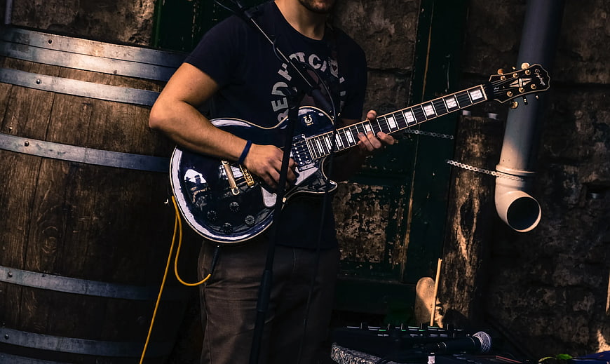 Musician Playing Black Electric Guitar on Stage