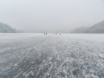 Skaters on a frozen lake in winter fog