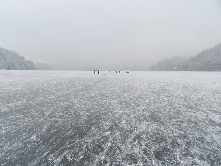 Skaters on a frozen lake in winter fog