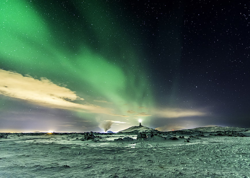 Vibrant green aurora borealis over snowy Icelandic landscape