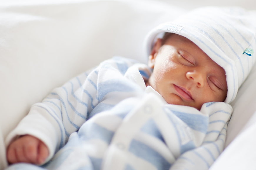 Sleeping newborn baby in blue striped outfit