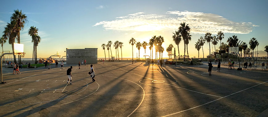 Panoramic Sunset Basketball Court with Palm Trees and Players