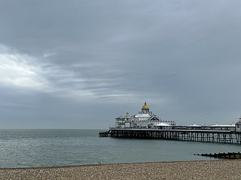 Brighton Palace Pier on a cloudy day with pebble beach foreground