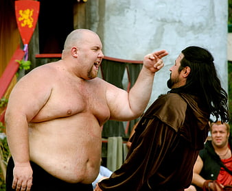 Shirtless man yelling at man in medieval costume