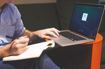 Man working on laptop and writing in notebook