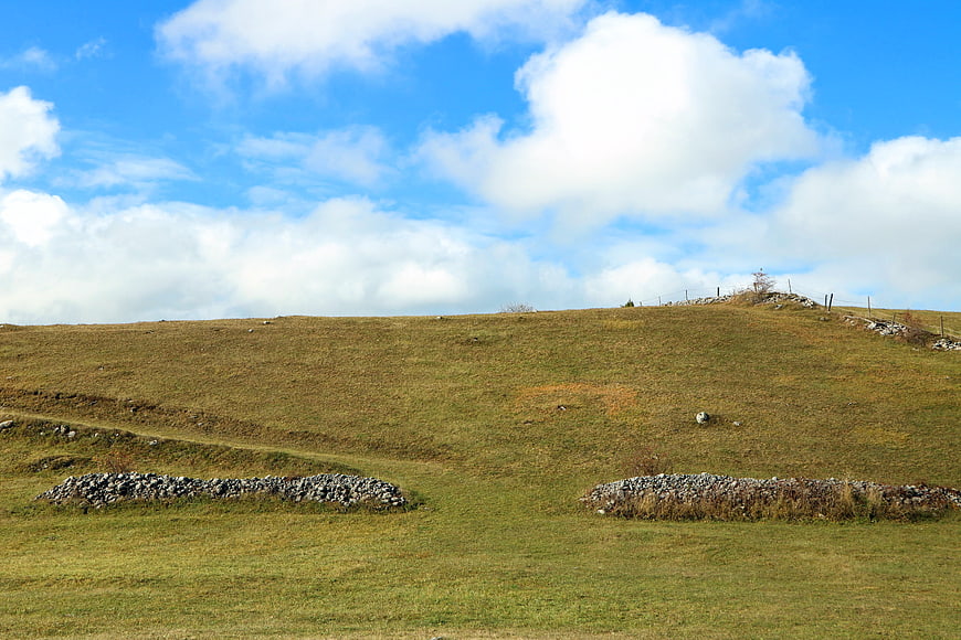 Rolling grassy hills with stone walls under blue sky