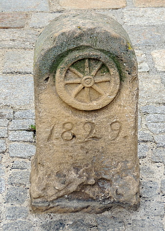 Old stone milestone with carved wheel and date 1829