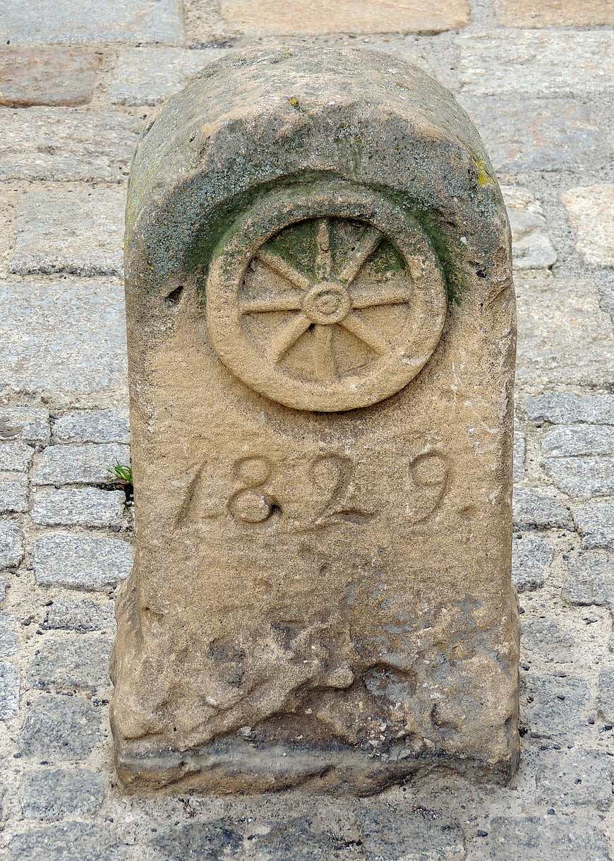 Old stone milestone with carved wheel and date 1829