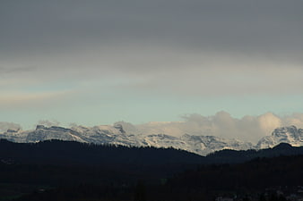 Snow-Capped Mountain Range with Dark Forest Foreground
