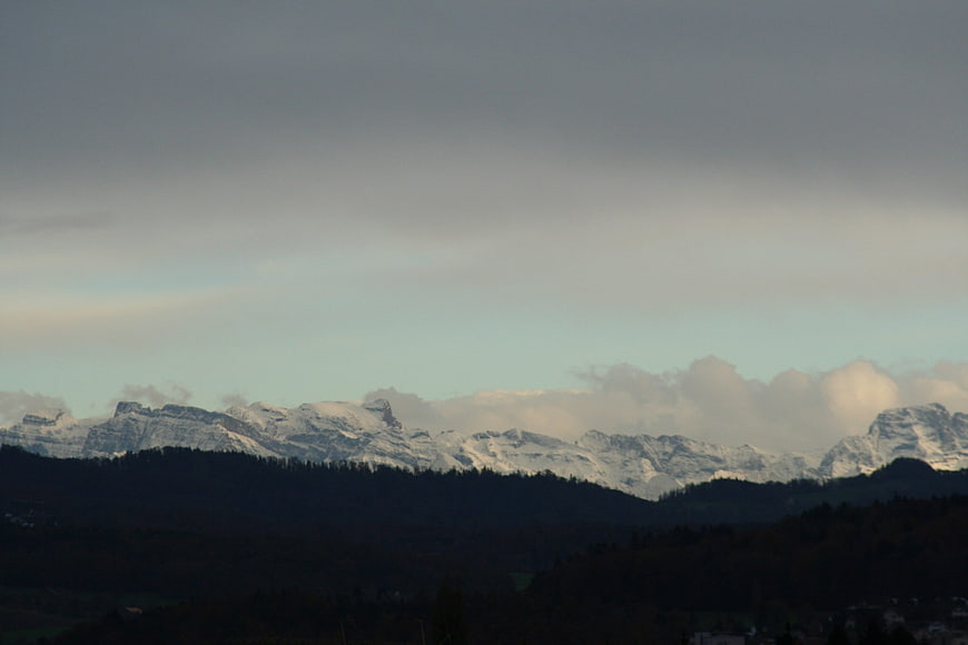 Snow-Capped Mountain Range with Dark Forest Foreground