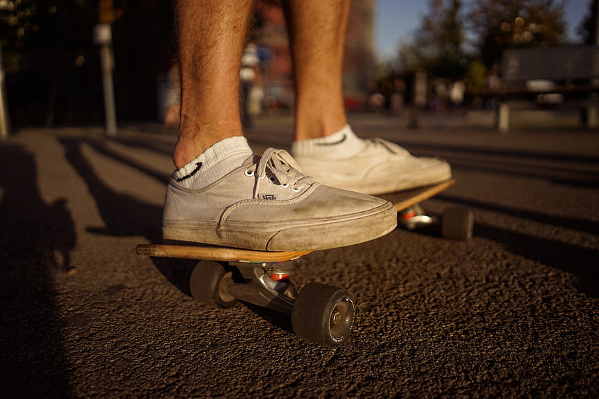 Close-up of feet on skateboard in golden hour light