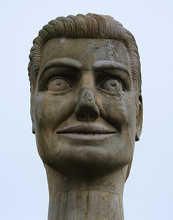 Close-up of weathered stone head sculpture against sky