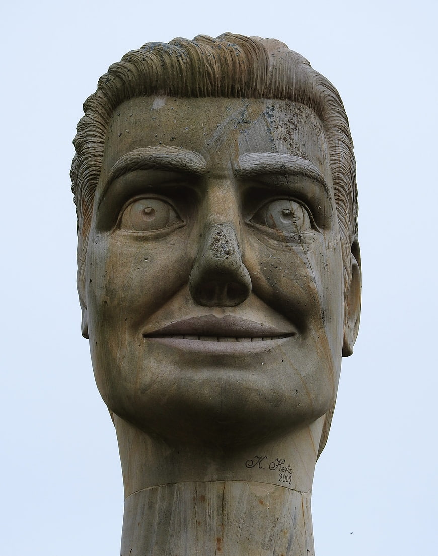 Close-up of weathered stone head sculpture against sky