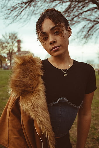 Young woman with curly hair and fur jacket in park