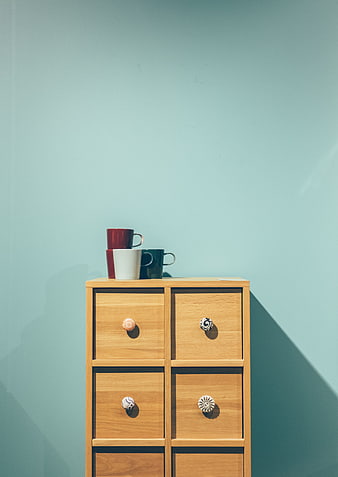 Minimalist wooden cabinet with colorful mugs on pastel wall