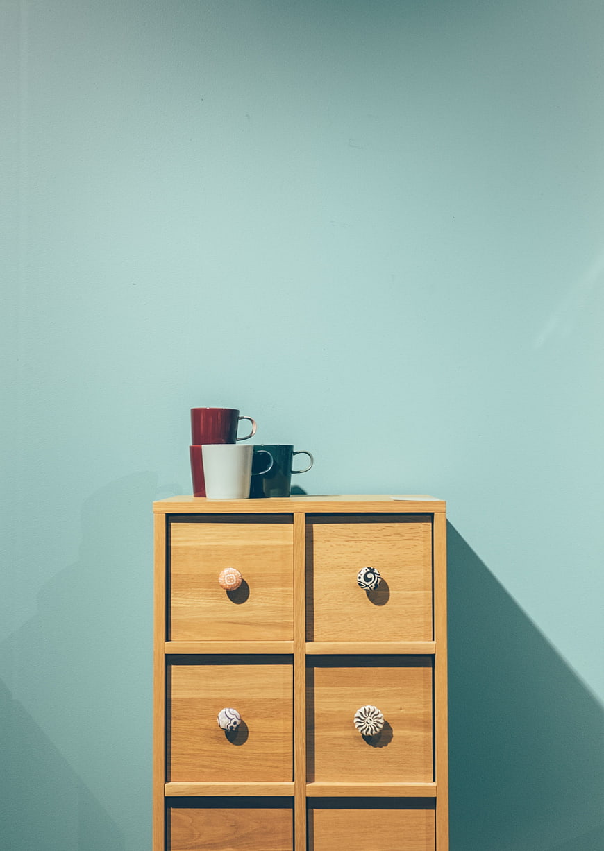 Minimalist wooden cabinet with colorful mugs on pastel wall
