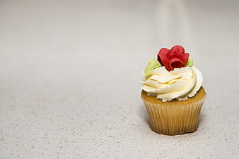 Decorated Vanilla Cupcake With Red Rose Topping On Light Surface