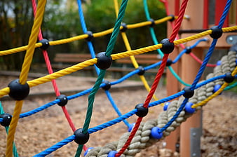 Close-up of colorful playground rope climbing net with wooden structure