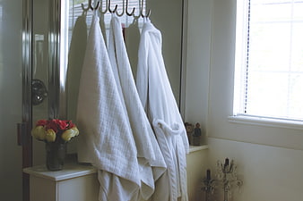 White Bath Towels and Robe Hanging in Bright Bathroom