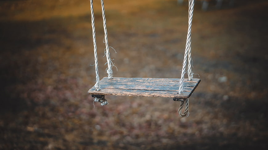 Empty Weathered Wooden Swing With Ropes Against Blurred Earthy Field