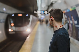 Man with orange headphones waiting for subway train