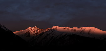 Snow-Capped Mountain Peaks Bathed in Alpenglow at Dusk