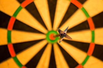 Dart hitting bullseye on dartboard close up