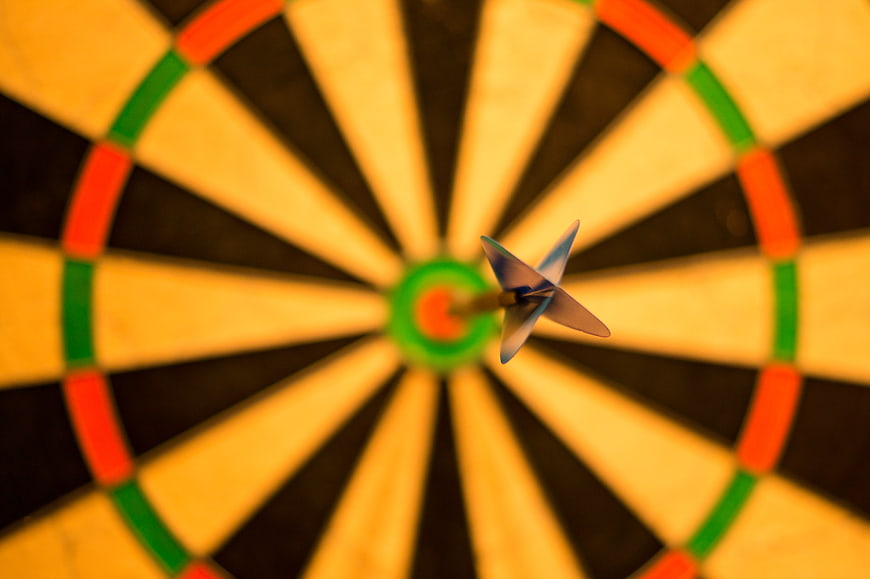 Dart hitting bullseye on dartboard close up