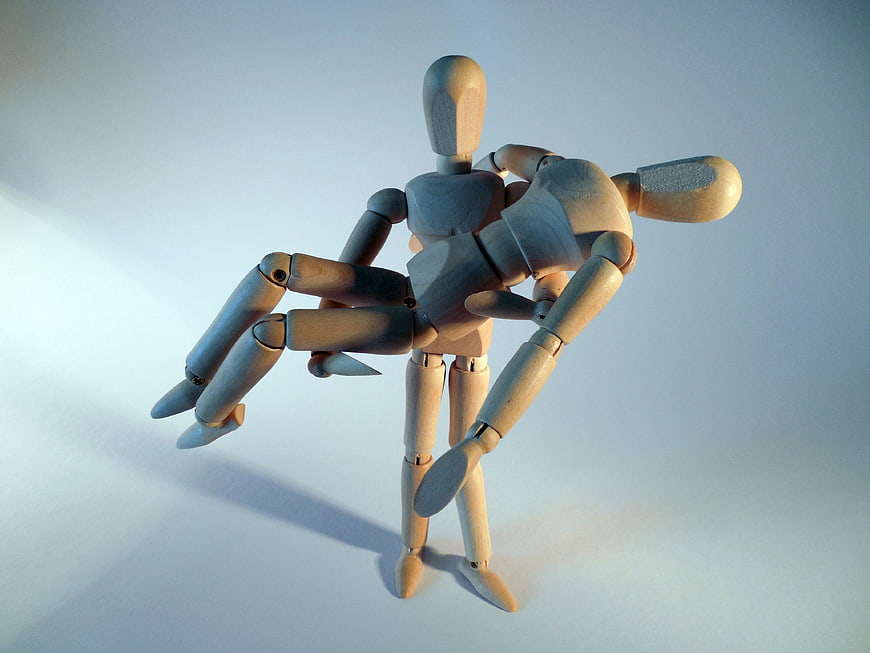 Wooden Articulated Puppet Carrying Another Figure on Light Background