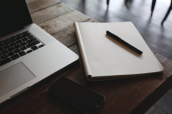 Laptop, smartphone, and notebook on rustic wooden desk