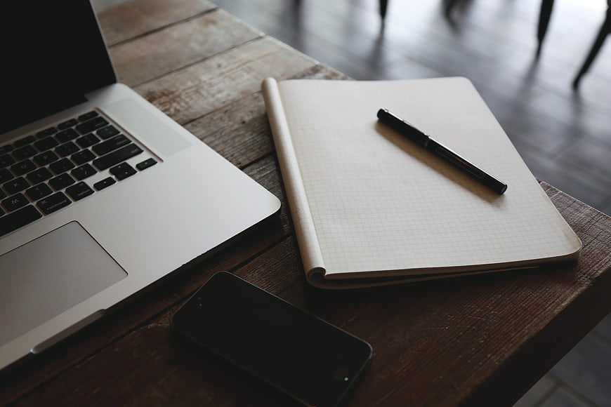 Laptop, smartphone, and notebook on rustic wooden desk