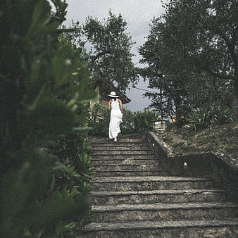 Woman in White Dress Walking Up Stone Steps in Nature