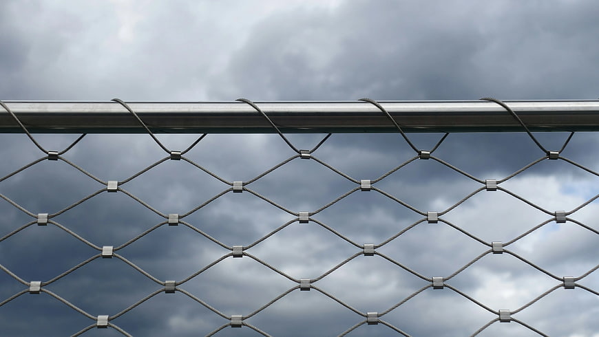 Metal Cable Mesh Fence Against Cloudy Sky