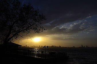 Dramatic Sunset Silhouette Over Lake With City Skyline