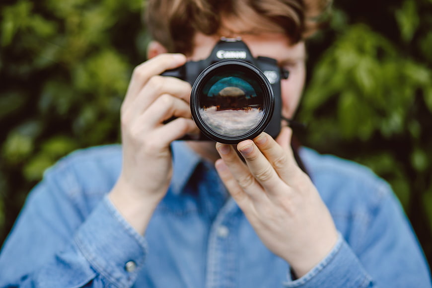 Photographer holding DSLR camera with lens reflection
