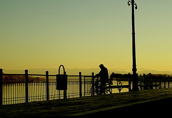 Silhouette of Man with Bicycle on Riverside Promenade at Sunset
